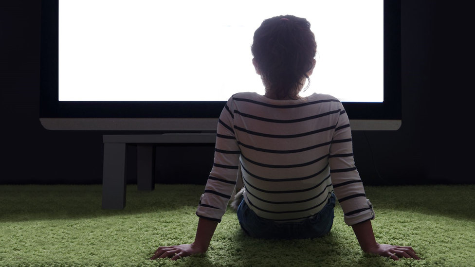 Child staring at a huge screen